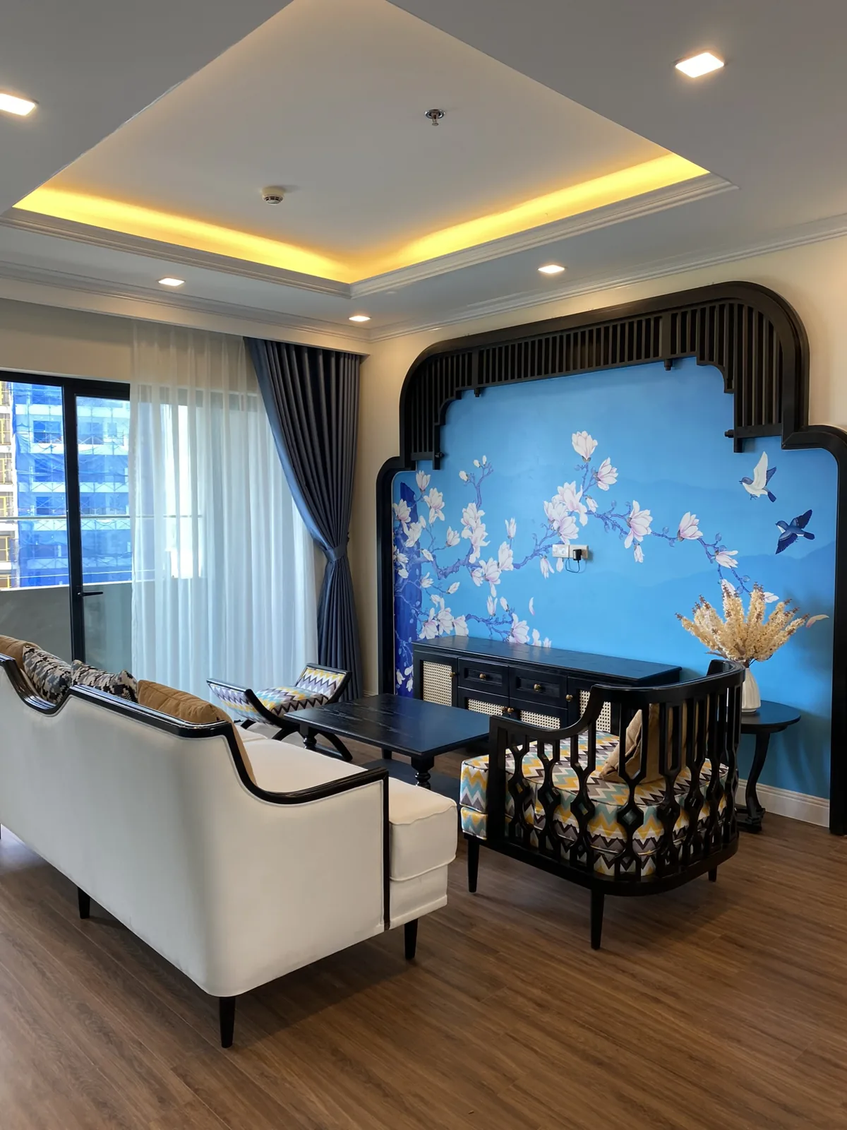 Phòng khách Indochine với mảng tường mộc lan xanh và khung gỗ đen uốn vòm