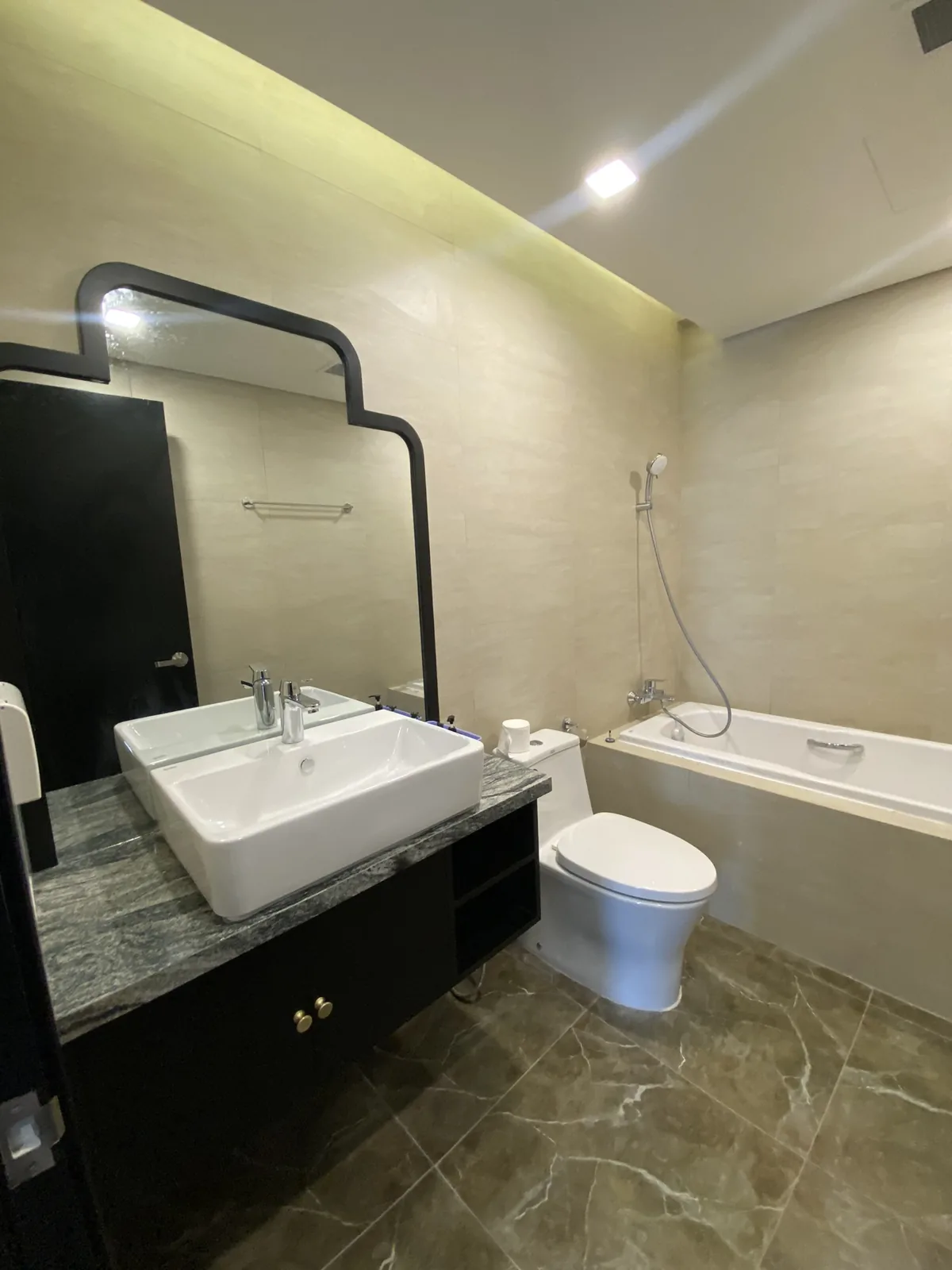 Phòng tắm với gương uốn khung đen trên mặt đá lavabo