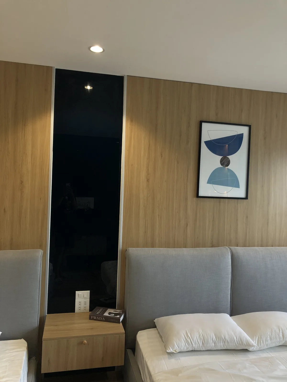 Chi tiết đầu giường với tủ gỗ, tranh treo và mảng tường xanh